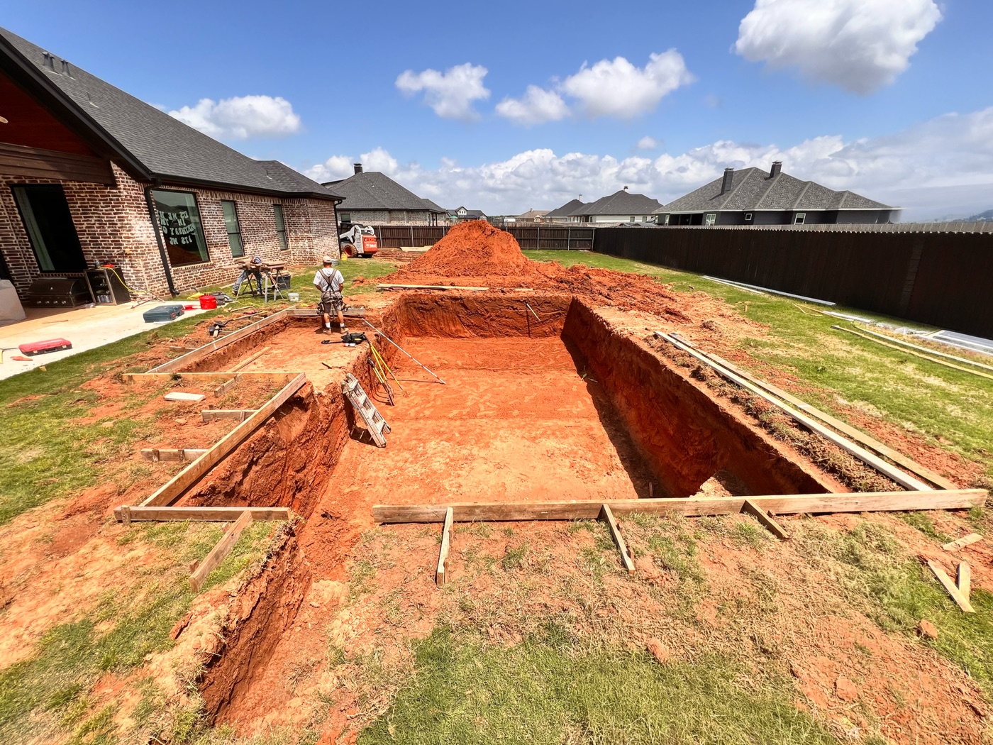 Excavated pool shell dug out in red West Texas soil with wood forms set