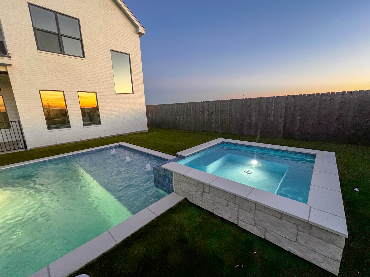 Finished pool with stone-faced raised spa and bubblers at dusk