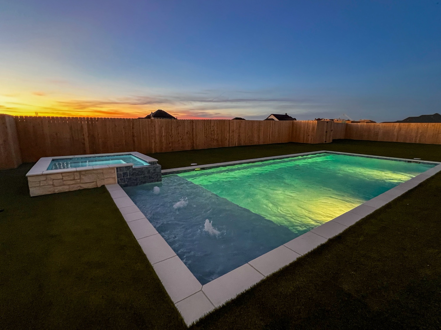 Finished pool and raised spa lit green and blue at sunset