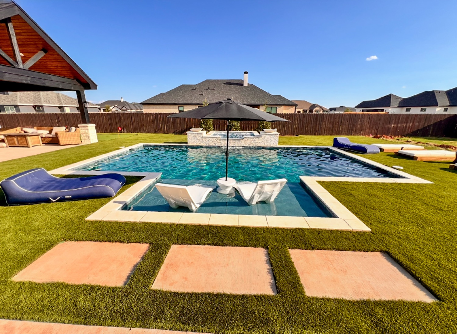 Finished pool with tanning ledge, raised spa, and a backyard putting green